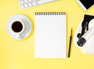 Wall Mural - Top view of yellow office desktop with microscope, notepad, computer, smartphone. Mock up, empty space, science template