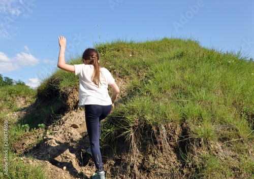 Child Blonde Girl With Long Hair Climbing A Little Hill With
