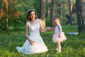 Mom and daughter are two years old sitting on the grass