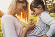 © iuricazac - Outdoor portrait of pretty mother and her kid playing outdoors, explore eco nature. Cute woman and her cheerful girl playing in the park. Portrait of happy family. Motherhood and childhood.