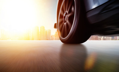 Low angle side view of car driving fast at sunset with motion speed effect .