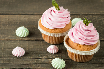 Closeup of cupcakes with vanilla, berries, pink and white cream, chocolate and sprinkles on wooden background. Selective focus. Sweet dessert tasty food concept muffin.