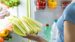 Woman taking fresh celery from the fridge