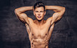 © Fxquadro - Close-up portrait of a sexy shirtless young man model with a muscular body and stylish haircut posing at a studio. Isolated on dark background.