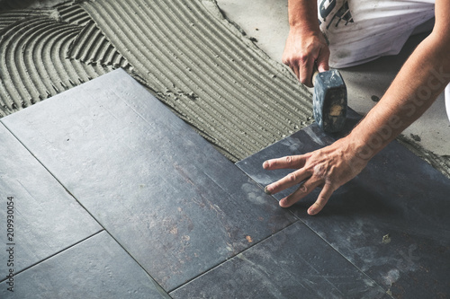 Cuadros en Lienzo Worker placing ceramic floor tiles on adhesive surface, leveling with rubber ham
