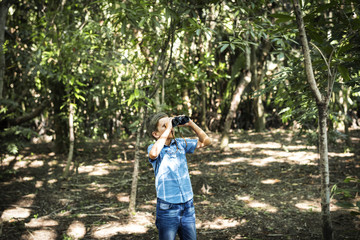 Wall Mural - Boy using binocular in the forest