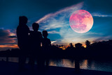 Fototapeta Londyn - Silhouette of mother with children looking at red super moon on sky.