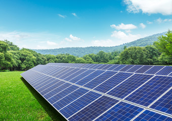 Solar panels and mountains in green grass field