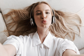 Wall Mural - Pretty young woman indoors at home listening music