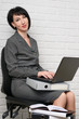 © soleg - business woman with laptop and folders, dressed in a gray suit poses in front of a white wall