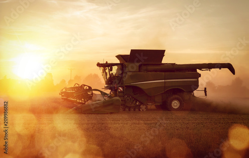 Fotografía Mähdrescher auf dem Feld bei Sonnenuntergang