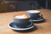 Closeup Image Of Two Blue Cups Of Hot Latte Coffee With Latte Art On Vintage Wooden Table In Cafe
