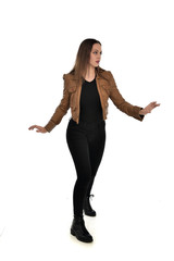 full length portrait of brunette girl wearing brown leather jacket.   standing pose on white background.