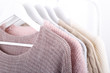 Warm knitted, autumn, winter clothes hanging on a rack, trending concept,pastel colors