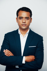 Portrait of confident Indian businessman standing cross-armed on white background