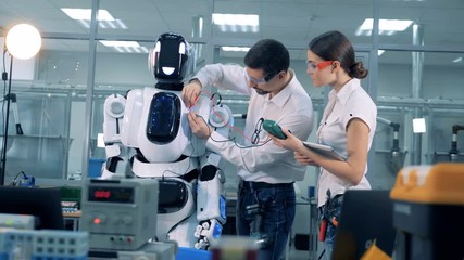Two workers gauge voltage of a cyborg.