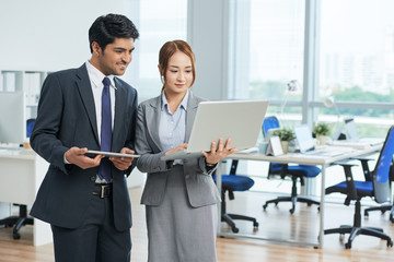 Business partners using laptop together in team while standing at office