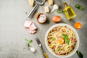 Wall Mural - Traditional italian pasta, spaghetti carbonara with bacon, creamy sauce, parmesan cheese, egg yolk and fresh basil leaves grey stone background copy space