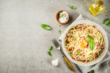 Wall Mural - Traditional italian pasta, spaghetti carbonara with bacon, creamy sauce, parmesan cheese, egg yolk and fresh basil leaves grey stone background copy space