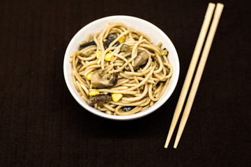 Plate of asian noddles in a white round bowl with chopsticks