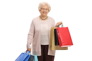 Canvas Print - Elderly woman with shopping bags looking at the camera and smiling