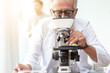 © thbangkok - Doctor older or seriously scientist working with a microscope in Laboratory.