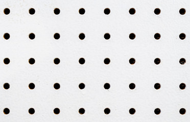 Close-up of symetrical holes on a white pegboard