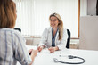 © bnenin - Blonde general practitioner holding eyeglasses while talking to a female patient.