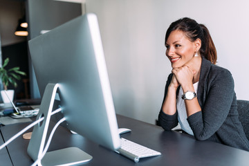 Wall Mural - Attractive female office worker looking at computer screen.