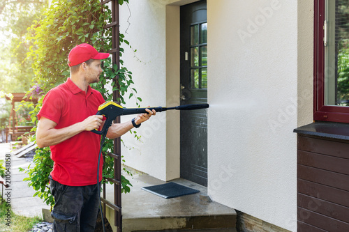 Fotografía worker with high pressure washer cleaning house facade