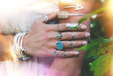 Fototapeta Boho - closeup of young woman hand and arm with lot of boho style jewrly, rings and bracelets outdoor light leak