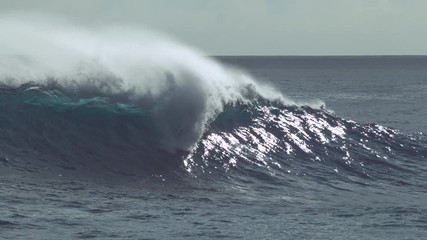 Wall Mural - SLOW MOTION, CLOSE UP: Big glistening ocean wave crashes into the rocky shore of the Easter Island. Spectacular shot of massive barrel wave approaching small tropical island on a perfect summer day.