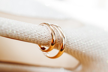 Golden wedding rings on bride shoes with rhinestones. Wedding jewelry details. Symbol of love and marriage.