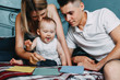 © Vadym - Little child and parents playing colorful training cards and learning the colors sitting together at home bed. Early development, educational play for kids