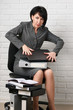 © soleg - angry business woman with laptop and folders having stress, dressed in a gray suit poses in front of a white wall