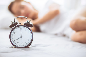 Wall Mural - Beautiful asian young woman turn off alarm clock in good morning, wake up for sleep with closeup foreground alarm clock, relax and lifestyle concept.