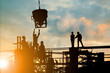 © Yuttana Studio - Silhouette of engineer and construction team working at site over blurred background sunset pastel for industry background with Light fair.Create from multiple reference images together.