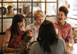 Diverse group of girlfriends laughing together in a trendy bar