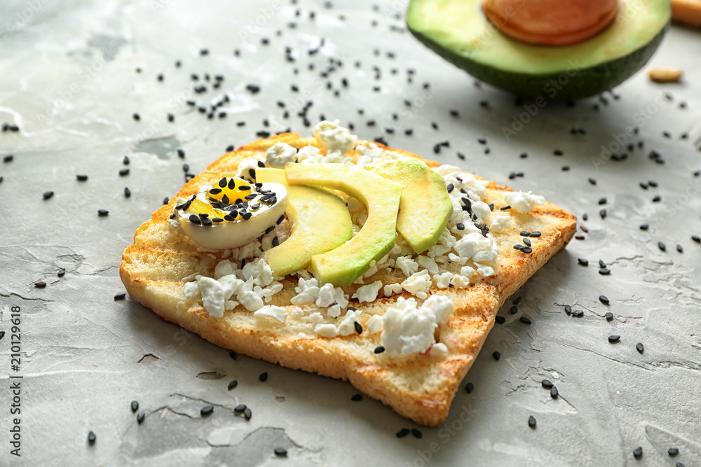 Tasty toast with avocado on grey background