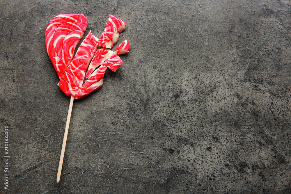 Cracked heart-shaped lollipop on grey background