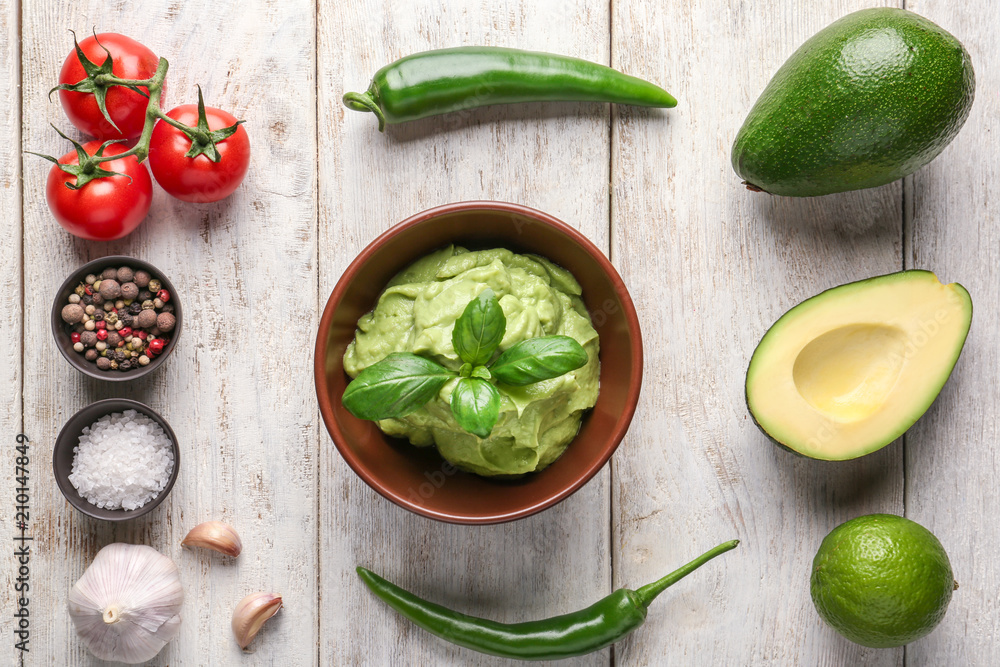 Composition with tasty guacamole, spices and vegetables on wooden background