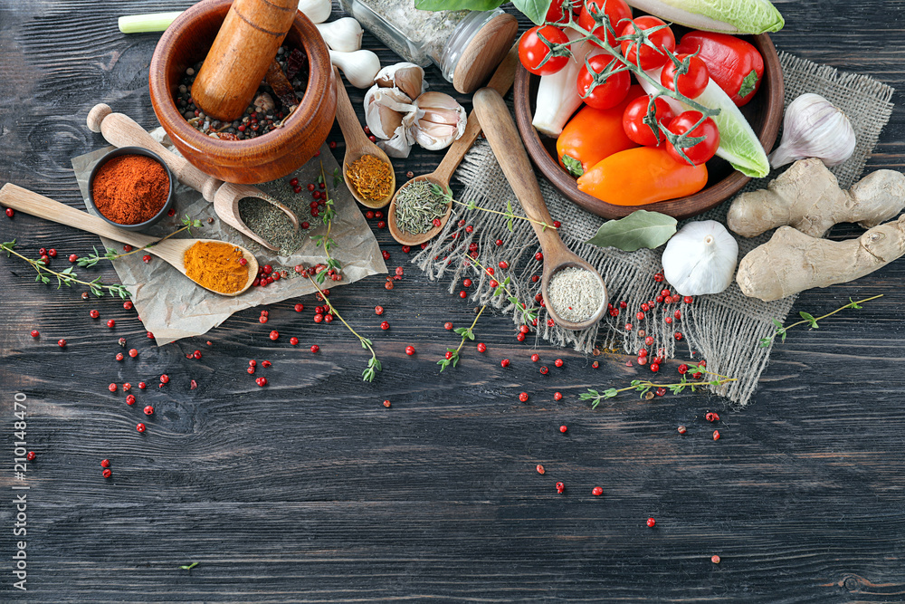 Different kinds of spices with vegetables on wooden background