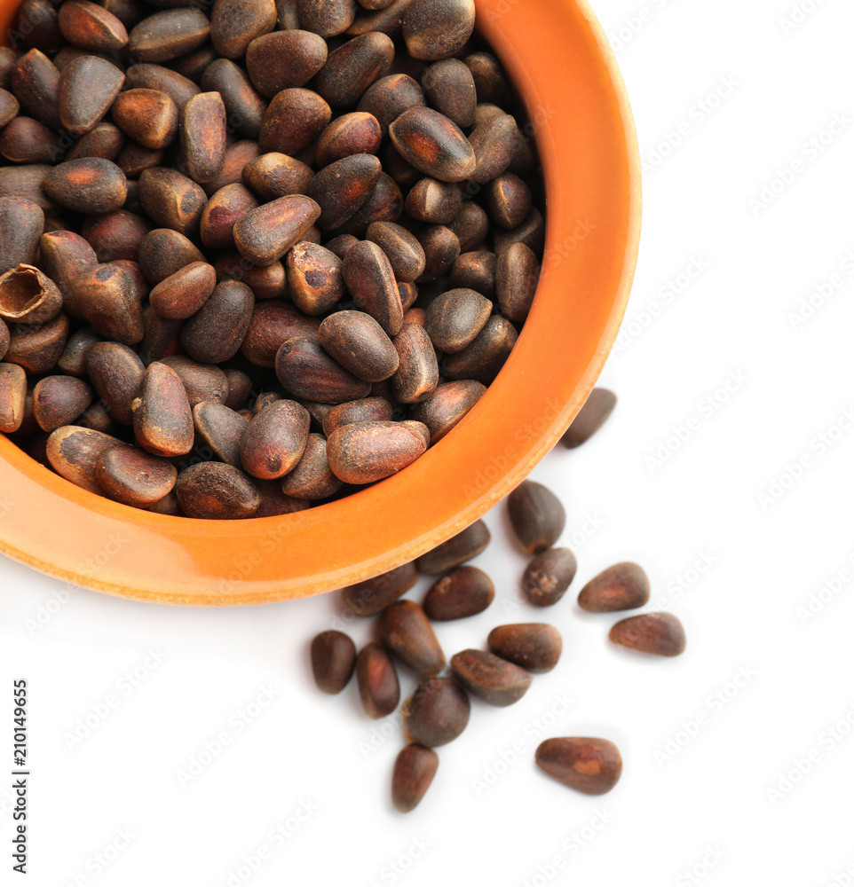 Bowl with pine nuts on white background