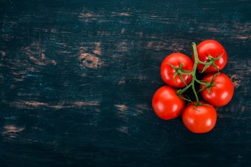 Wall Mural - Red Fresh Tomatoes on a twig. On a wooden background. Top view. Copy space.