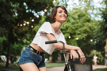 Wall Mural - Pretty young girl in summer clothes sitting on a bicycle