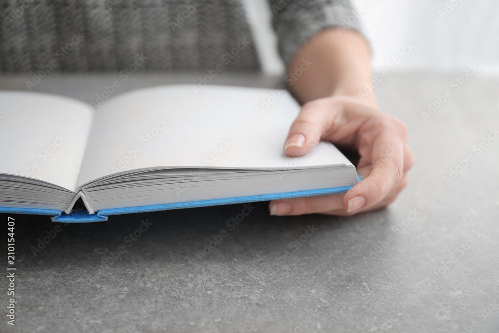 Young woman reading book at table, closeup