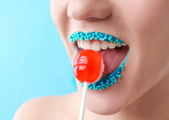 Sticker - Beautiful young woman with creative makeup and lollipop on color background, closeup