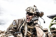 Special forces soldier, military communications operator or maintainer in helmet and glasses, screaming in radio during battle in desert. Calling up reinforcements, reporting situation on battlefield