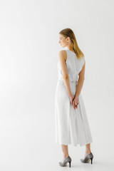 Wall Mural - rear view of attractive woman in linen white dress posing isolated on grey background