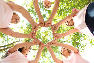 Sticker - Beautiful women of different ages with pink ribbons putting hands together outdoors. Breast cancer concept